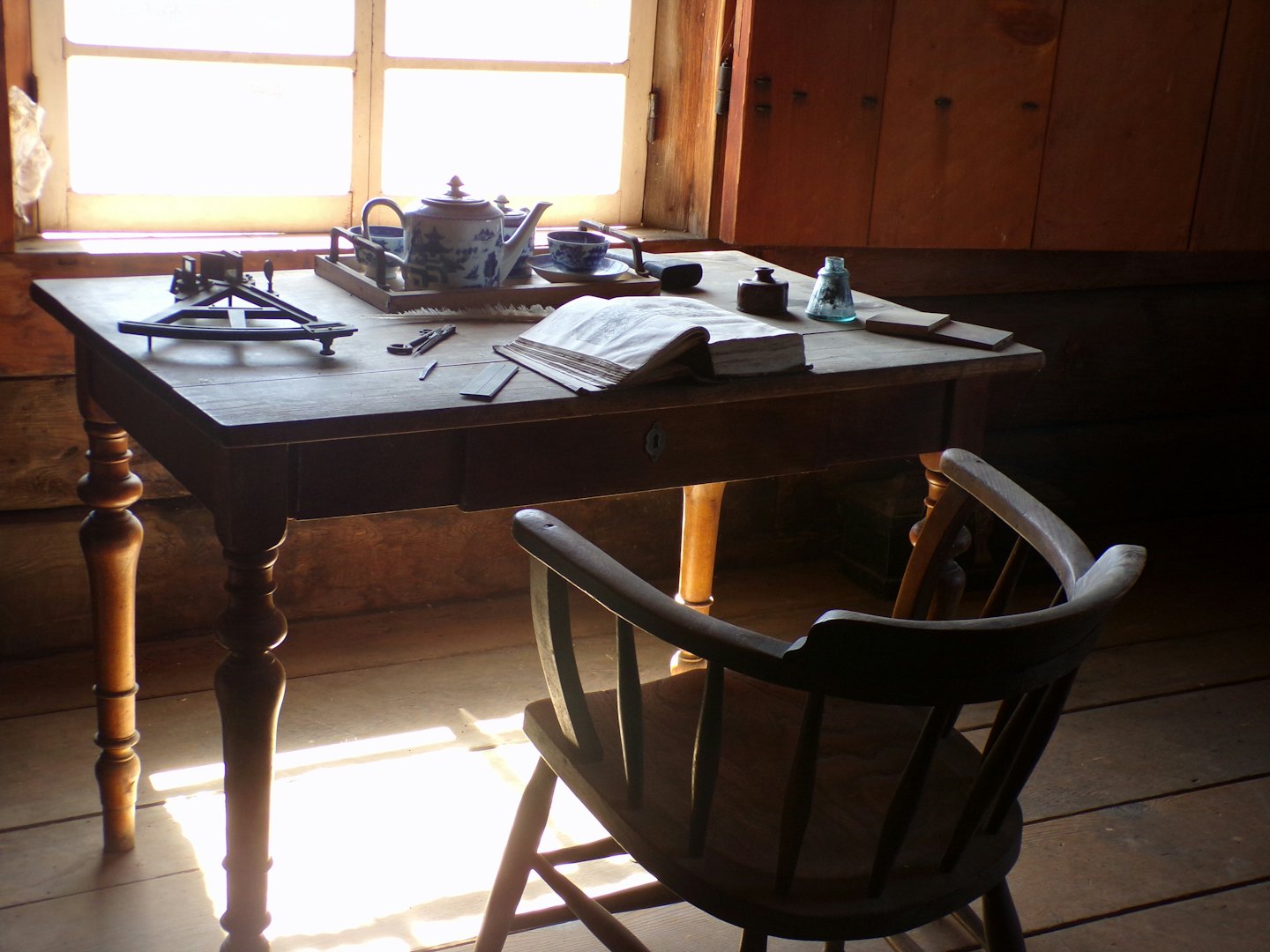 Antique wooden desk with writing instruments and tea set.