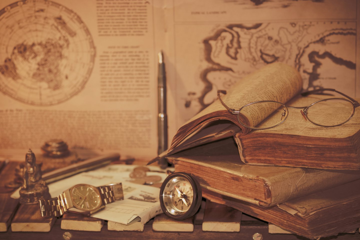 Antique books and navigational tools resting on a wooden desk.