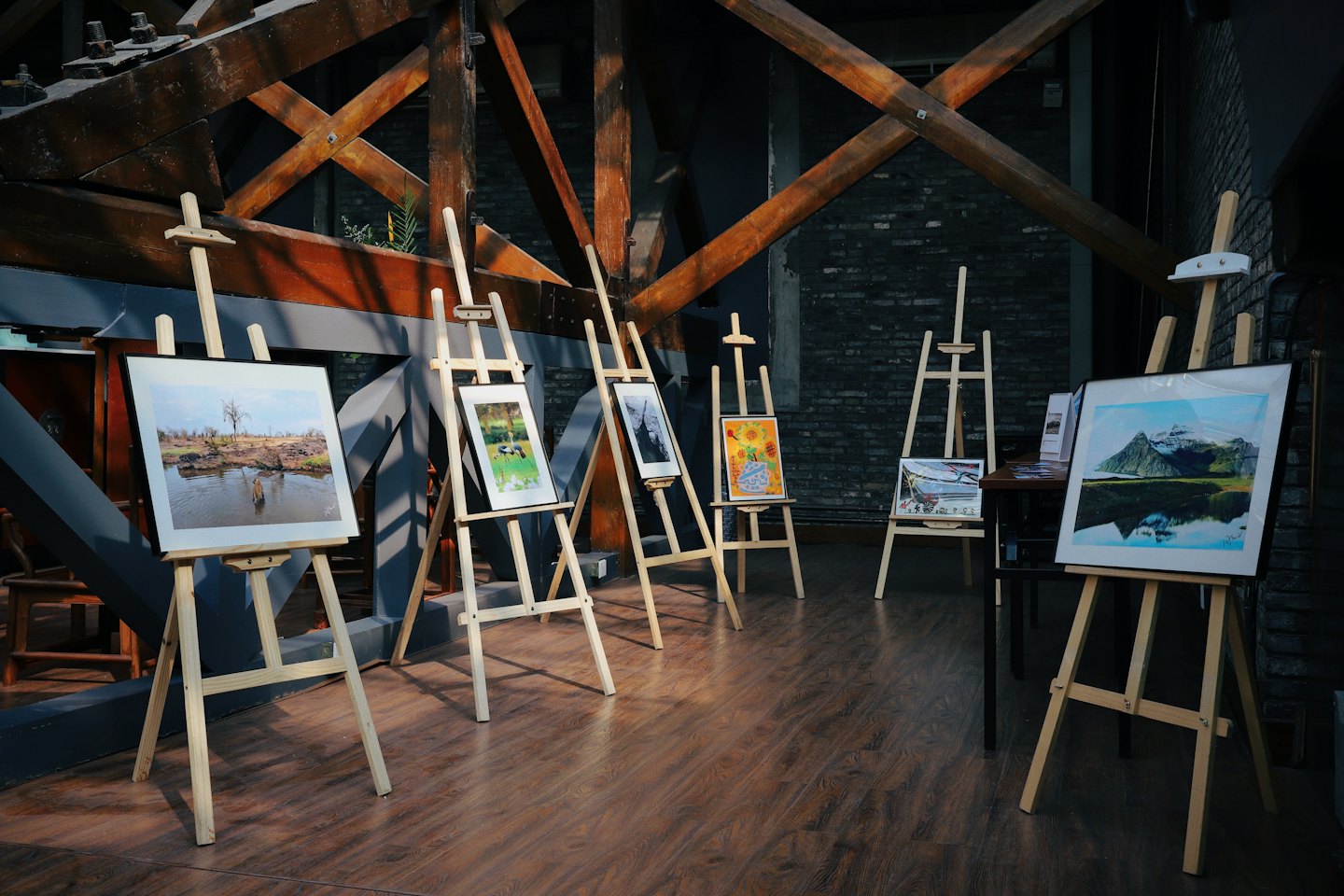 Art exhibition with framed artworks on wooden easels.